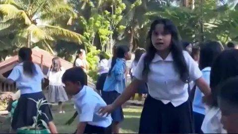  Children at a school in the Philippines shelter after an earthquake strikes, causing an outdoor structure to collapse