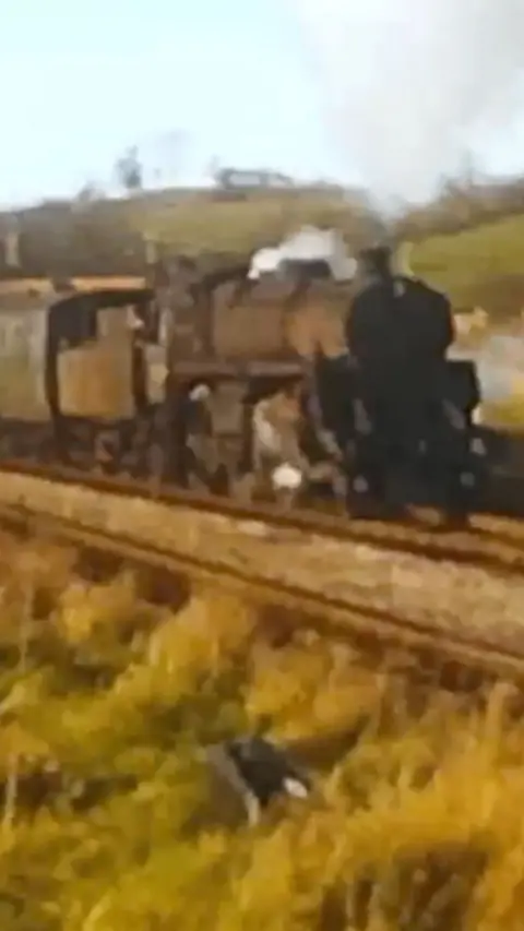 A still from an old, low-resolution film showing a steam train 