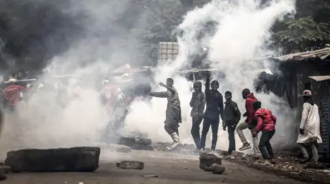 Protesters react amid clouds of tear gas fired by Kenya police officers during clashes at Saba Saba Day demonstrations in Nairobi on July 7, 2025