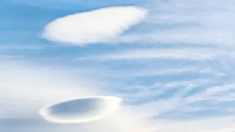Dove Rosalinda The image shows two flat and rounded lenticular clouds in a blue sky.