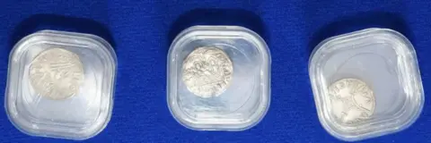 Durham Police Three small silver coins. each coin has different figures and inscriptions and is placed in a protective glass. 