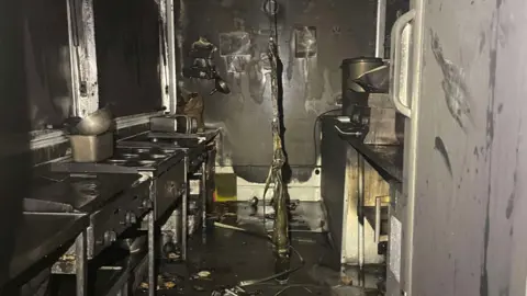 Jordan Jones Inside a van kitchen, soiled with ash and melted walls. 