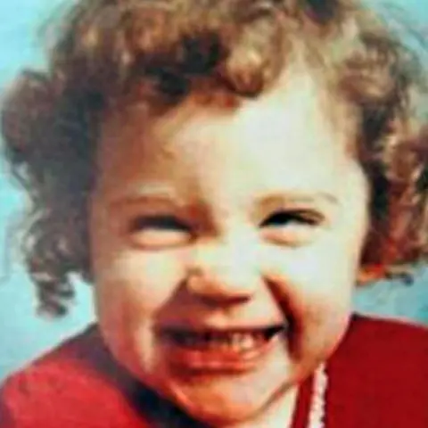 Family photo Katrice Lee grins at the camera. She has curly, light-brown hair and wears a red dress.