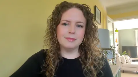 A view of Lisa Witherden in her room, looking at the camera during an online video interview.