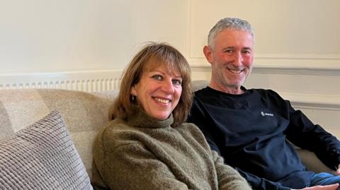 Amanda and Howard Gruber sitting on a sofa and smiling