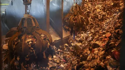 Getty Images Uma garra mecânica coletando resíduos para incineração em uma fábrica da Veolia no sul de Londres