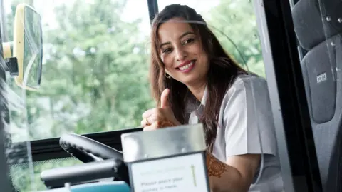 NCT Zohra Rani giving the thumbs up to a passenger leaving the bus while she is sat behind the wheel