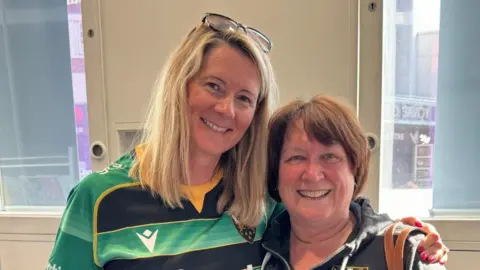 BBC/Rob Constantin Marianne with long blond hair and a Saints shirt and Lis with short brown hair