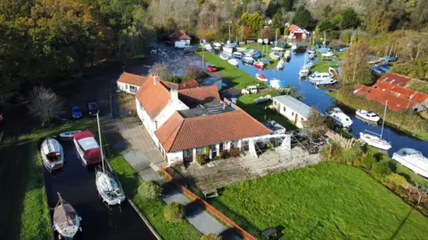 Shaun Whitmore/BBC Ariel view of pub and broad waterway with boats