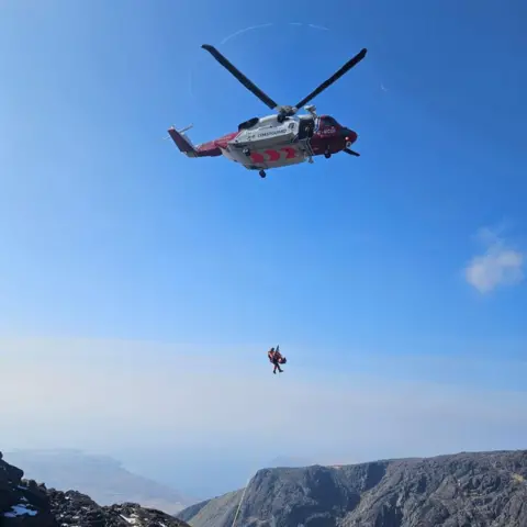 David Sked The red and white helicopter hovers as it winches the casualty and a paramedic onboard.