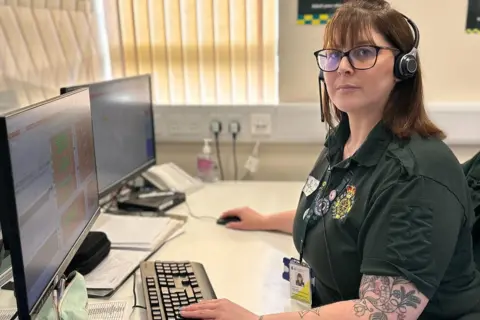 Welsh Ambulance Service Emma Worrell at her desk wearing headset