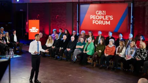 GB News Former Prime Minister Rishi Sunak, wearing a suit with a white shirt and blue tie, appears in front of an audience of people and a sign which reads "GB People's Forum".