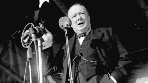 Winston Churchill in 1945 speaking at a microphone