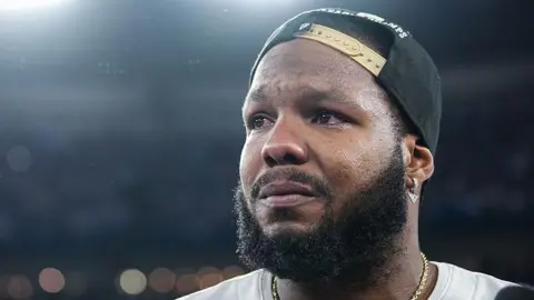 Getty Images Toronto Blue Jays first baseman Vladimir Guerrero Jr. (27) gets emotional after the game as the Toronto Blue Jays play the Seattle Mariners in Game 7 of the ALCS MLB Playoff Series at Rogers Center in Toronto. October 20, 2025. He's wearing a black backwards baseball cap and a white Blue Jays jersey. The photo is taken from a low angle, focusing on his face as he looks out at the crowd.