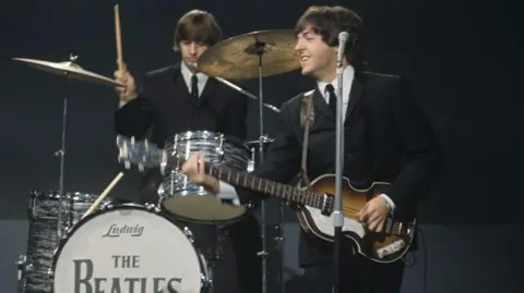 Getty Images Ringo Starr drumming behind Beatles bandmate and bassist/singer Paul McCartney in 1964