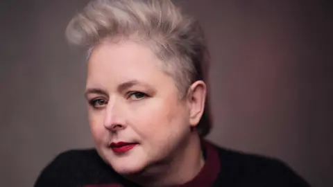 Headshot of Siobhán McSweeney wearing a black and red jumper