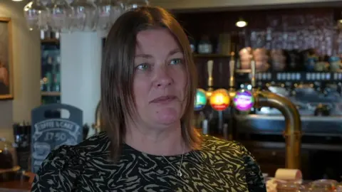 BBC Pier House deputy general manager Tamsyn McDonnell is standing in front of a bar with beer pumps. She is wearing a black and brown top.