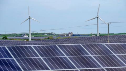 Wind farm seen behind solar energy panels