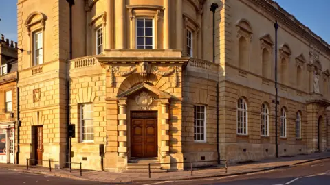Victoria Art Gallery The entrance to Victoria Art Gallery. The building is made of Bath stone and has a wooden door.