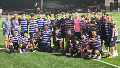 La Federación de Fútbol de las Islas Marshall de Marshall Islands, la primera pose del equipo internacional de Marshall Islands para un disparo grupal después de enfrentar a las Islas Vírgenes de los Estados Unidos el jueves en Springdale, Arkansas. Están en el campo, mirando hacia otro lado de la cámara.