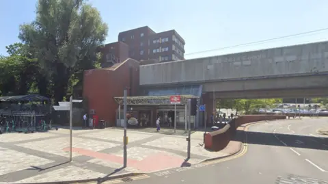 Google A street view of Basildon Train station. The entrance is under a road bridge, with a train station sign outside. 