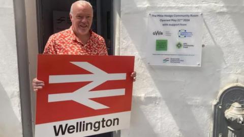 David Northey holds the new Wellington railway sign