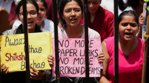 Reuters A group of three students during a protest carrying banners demanding an end to paper leaks.