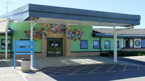 The front entrance of Uplands School in Swindon with bright green-painted walls and a colourful display of artistic decorations above the double doors.