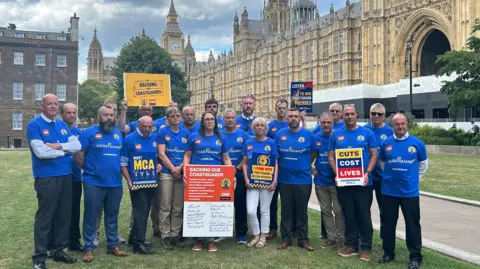 A group of coastguards - men and women - with protest placards outside the House of Commons.