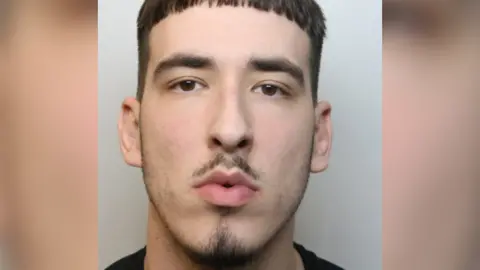 Wiltshire Police A mugshot of Oskar Krzeszewski. He has a small moustache and goatee and is wearing a black top.