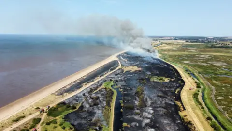 Andrew Waddison Smoke billowing from a wildfire at Wild Ken Hill in Snettisham, Norfolk. Part of the land is charred. The picture has been taken from above.