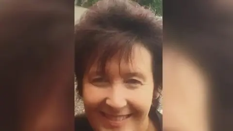 PA Media Paula Leeson smiles in a cropped photo. She has brown hair and a long fringe.