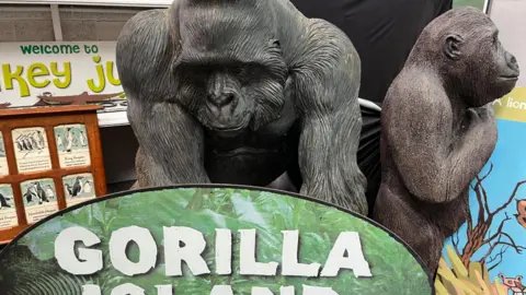 Two large gorilla sculptures that are for sale in the auction with the gorilla island sign