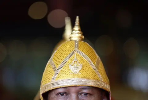 NARONG SANGNAK/EPA A Royal Thai Navy boatman participates in a Royal Barge worship ceremony to honor the King's 72nd birthday celebrations in Bangkok, Thailand, July 2, 2024. The photo shows a close-up of the boatman's eyes and helmet, which are designed in gold.