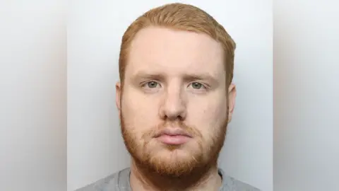 Thames Valley Police A custody image of James Bubb, facing forward with blank expression, in a grey t shirt and he has a ginger beard and pale face.