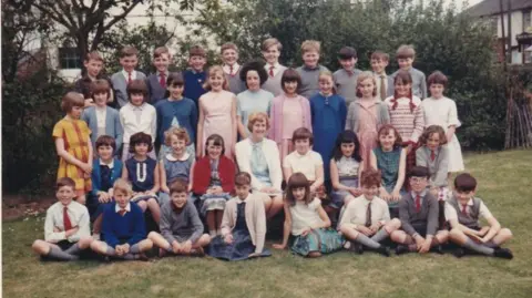 Handout A 1966 colour image of Miss Arnold's class at Loose Primary School in Kent standing and sitting in four rows 