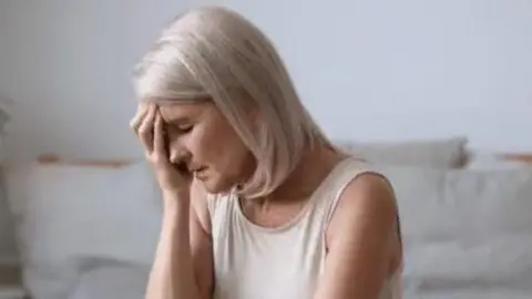 Generic image of woman in anguish. Shje has blonde greying hair and is wearing a white vest