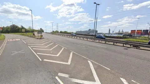 Dual carriageway road with docks and cruise ship seen to the right.