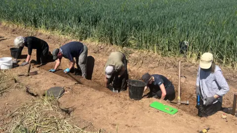 Archaeologists in a trench at site of lost medieval settlement.