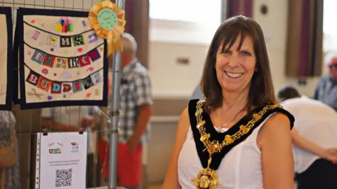 Gail Foster Photography A woman wearing a mayoral chain stood in front of a sign which says 'the Banner Buddies'.