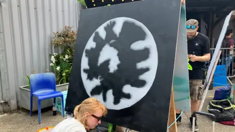 An artist painting on a black and grey canvas