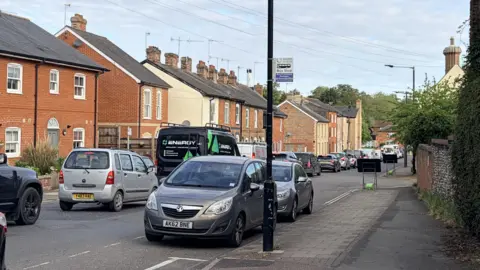 A queue of cars on a residential street.
