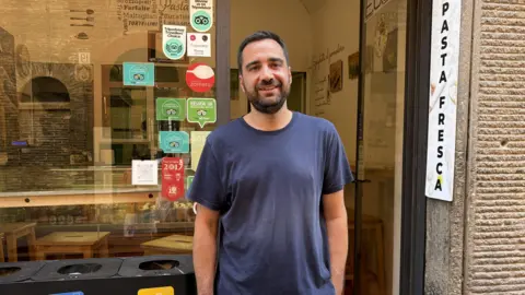 A man standing in front of a pasta shop