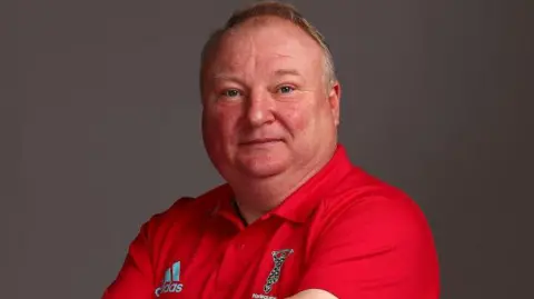 Getty Images A man with wispy hair looking at the camera. He is wearing a red Harlequins rugby polo shirt.