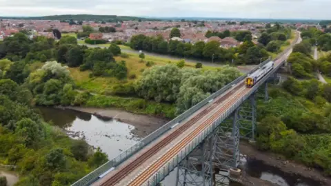 Northern A two-carriage train crosses a railway viaduct.