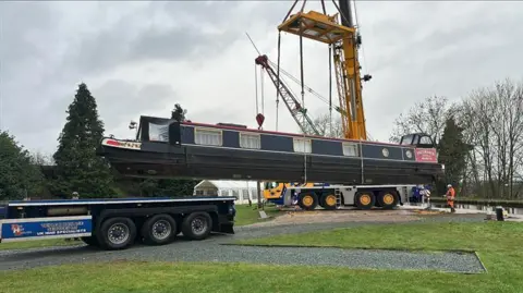 A boat is suspended in the air as it is being lifted out of Whitchurch Marina