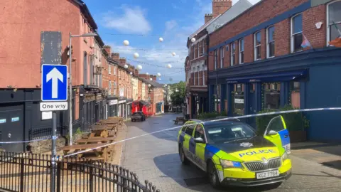 Police car on a street in Londonderry where a woman died following a fire in a flat