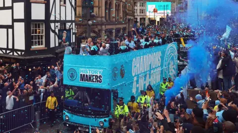 Reuters Manchester City's Erling Braut Haaland and Phil Foden with the Premier League trophy on the bus during the victory parade