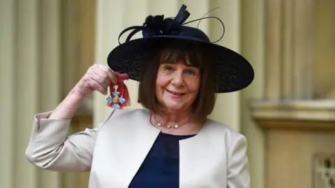 Julia Donaldson holding up a royal medal.