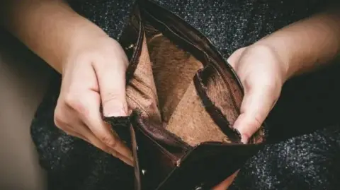 A person holding a wallet with no money inside it